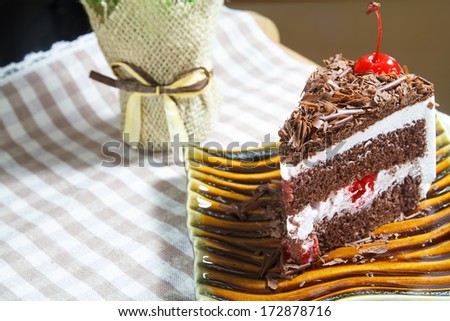 slice of delicious chocolate cake with chocolate icing and a cherry on top.