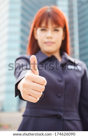 portrait of the smiling asian business woman that shows the thumbs up at modern building