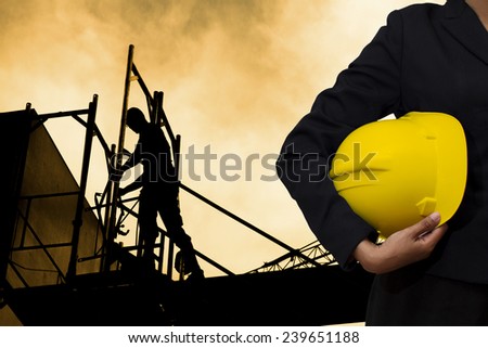 engineer holding Yellow helmet for workers security on background of building construction