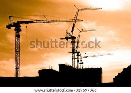 Silhouette of construction workers on scaffold working under a hot sun