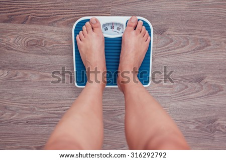 Girl is measuring her weight on the scales.