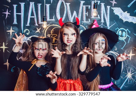 Girls, dressed up in Halloween costumes, show emotions of witches . Halloween party with group children.