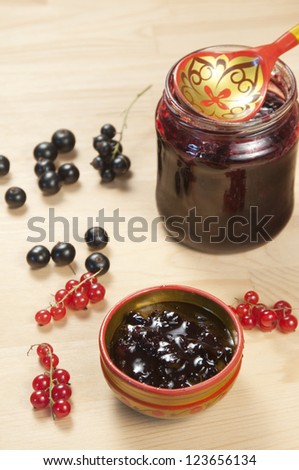 Black and red currant jam and berries on a wooden table
