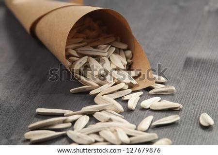 White sunflower seeds in a paper bag on a wooden table