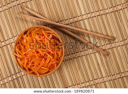 Korean Carrot Salad and chopsticks on a table with bamboo napkin