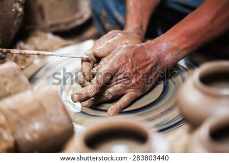 dirty hands making pottery in clay on whee