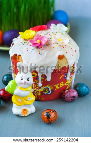 Easter cake figurine of a rabbit and colored eggs on green grass background