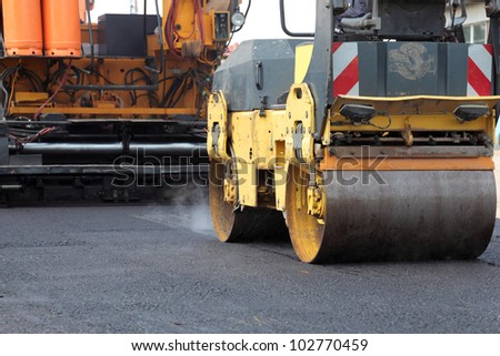 Road roller and asphalt paving machine at construction site