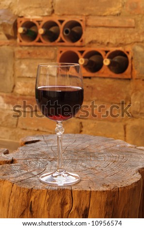 Glass of red wine on rustic wooden table in winery