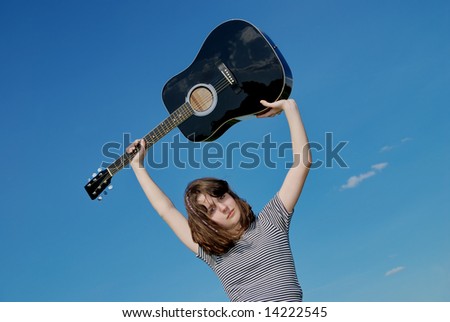 Teenage girl  with black guitar over blue sky