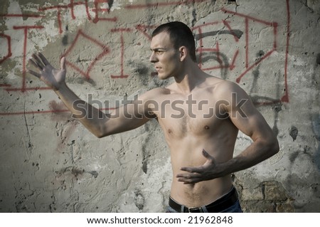 Shirtless muscular male model in front of the wall