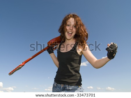 Red hair teenage girl with red electric guitar and blue sky