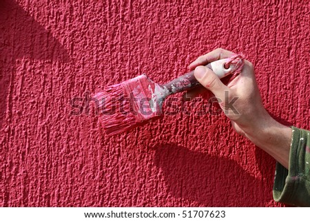 Painting of red wall with paint brush