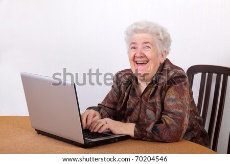 Portrait of laughing senior woman working at computer