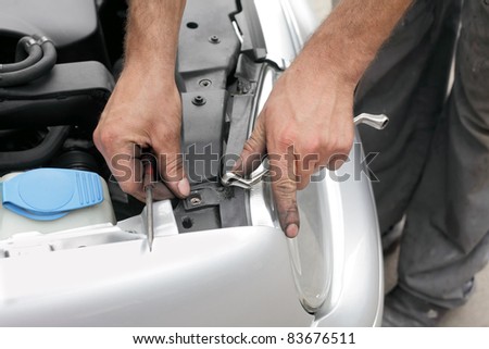 Repairing of modern car, workers hands fixing car light