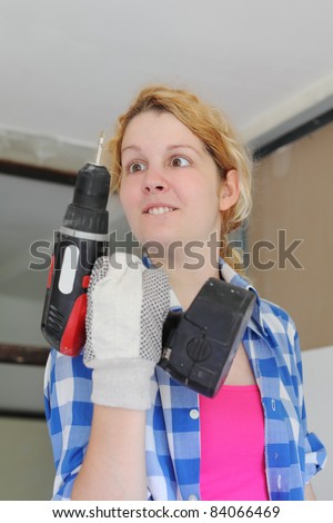 Young cross eyed girl looking to drill  in hand, working at home improvement