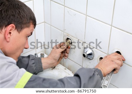 Plumber fixing pipeline  with tool in hands and checking leaking