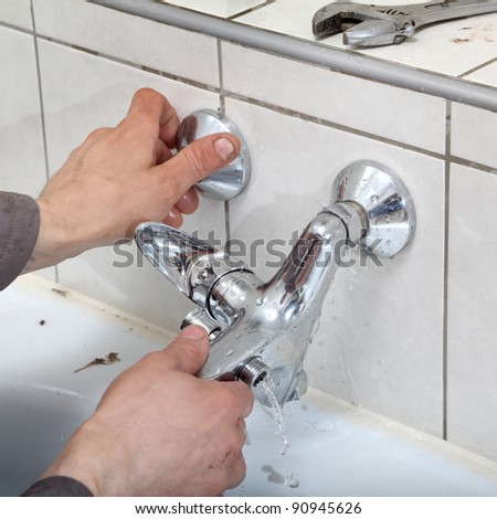 Plumber hands fixing water  tap with leaking water