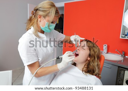 Female doctor cleaning and polishing  young patient tooth