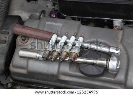 Modern car gasoline engine servicing,  ratchet tool and spark plug