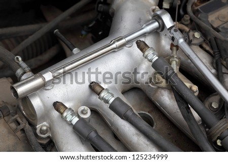Modern car gasoline engine servicing,  ratchet tool and spark plug