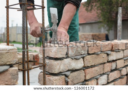 Mason hands making wall with mortar and bricks