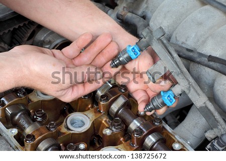 Car mechanic fixing fuel injector at  two camshaft gasoline engine