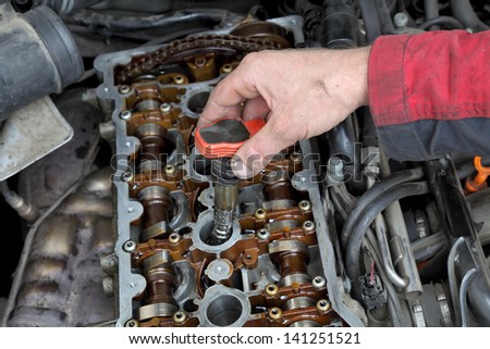 Car mechanic replacing ignition coil on gasoline engine