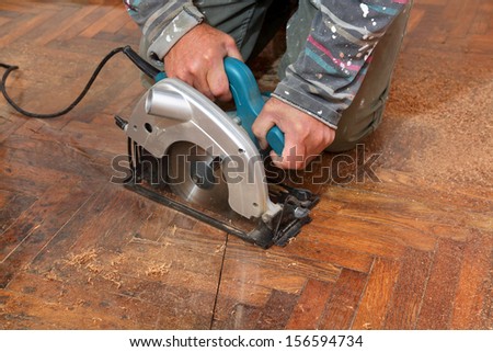 Worker cut old parquet floor with electric saw