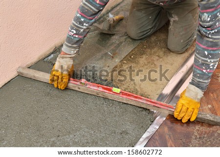 Home renovation, worker levelling concrete with level tool