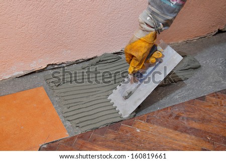 Home renovation, worker trowel spreading mortar for ceramic tile