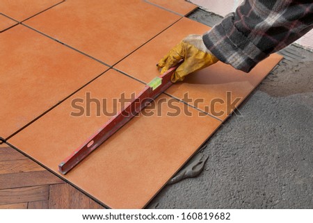 Home renovation, worker levelling tiles with level tool