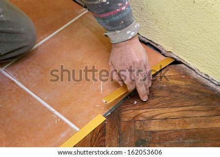Home renovation, worker installing tile trim profiles