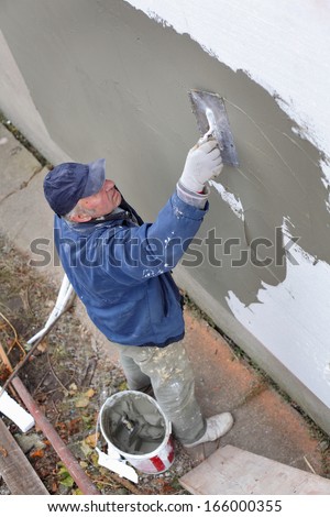 Worker Spreading Mortar Over Styrofoam Insulation With Trowel