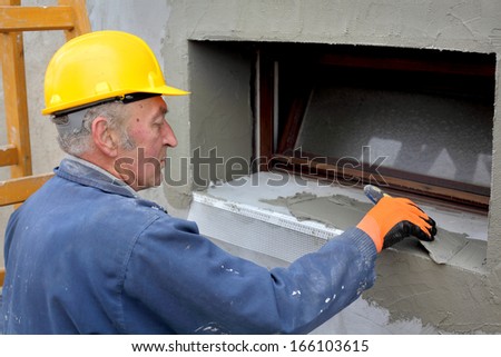 Worker spreading  mortar over styrofoam insulation with trowel
