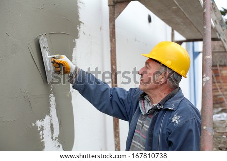 Worker spreading  mortar over styrofoam wall insulation with trowel