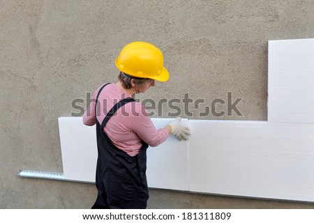 Female worker placing styrofoam sheet insulation to the wall