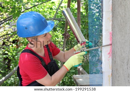 Worker applying polyurethane expanding foam glue with gun applicator