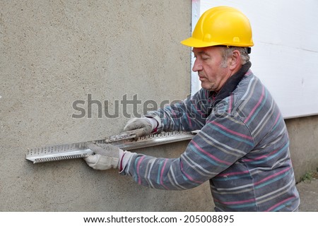 Worker placing aluminum batten for styrofoam sheet insulation to the wall