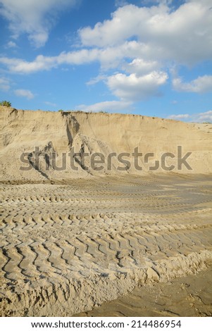 Sand quarry, heap of sand with tire tracks, landscape with beautiful sky