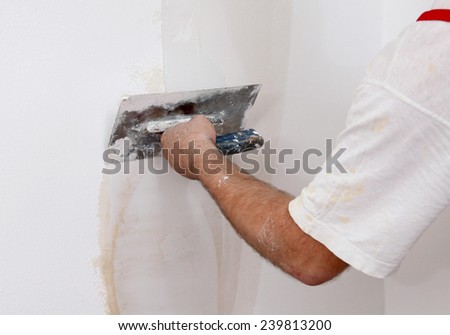 Worker spreading  plaster to wall with trowel, repairing works
