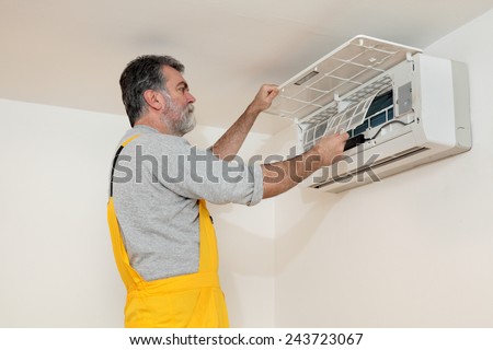 Electrician cleaning filter of air condition device in a room