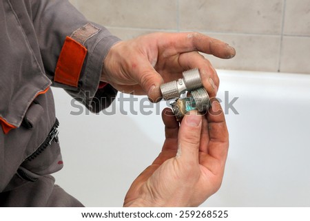 Plumber examine part of tube, pipe fitting, holding it in hands