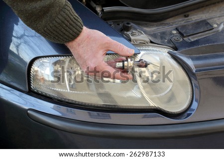 Human hand holding broken H4 car light bulb, mechanic servicing light