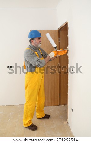 Worker install door, using polyurethane foam to fix it at wall
