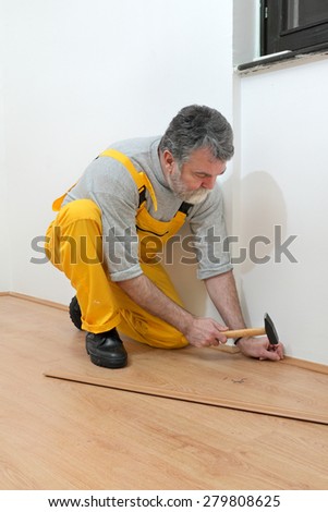Worker pound in a nail to batten for laminate floor, hammer nail,  floating wood tile