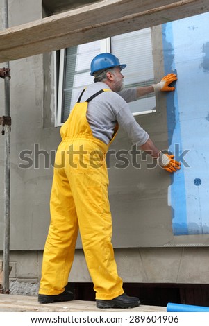 Worker placing mesh over styrofoam insulation and mortar