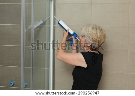 Woman using silicone cartridge for fixing aluminum batten of shower cabin