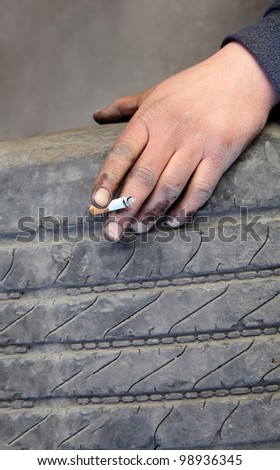 Worker break, hand with cigarette and old tire