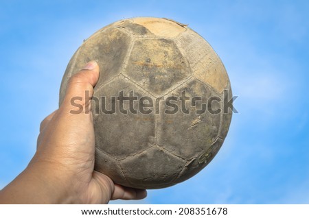old soccer ball in hand and blue sky